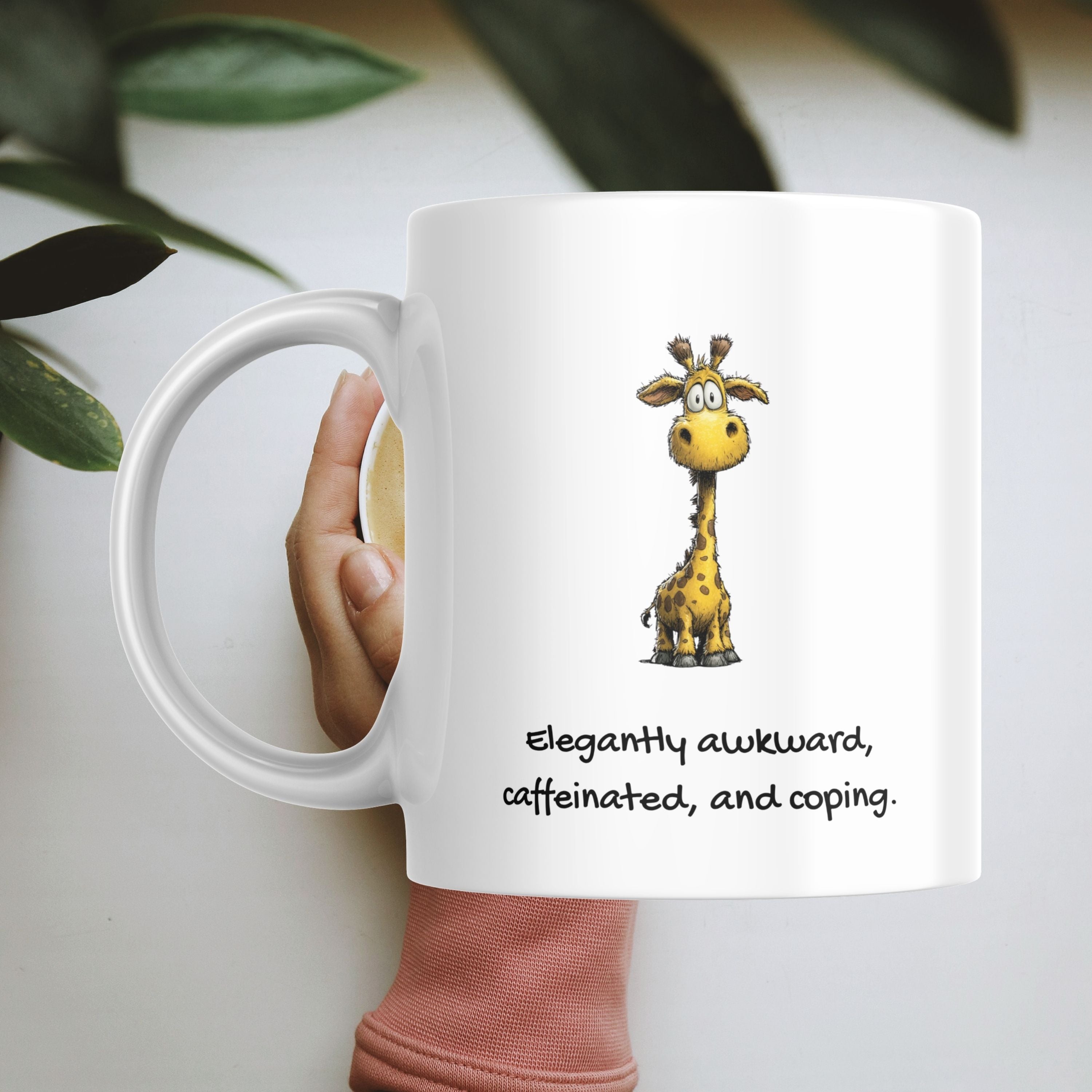 White mug with a cartoon giraffe and text, held by a hand, on a light background.