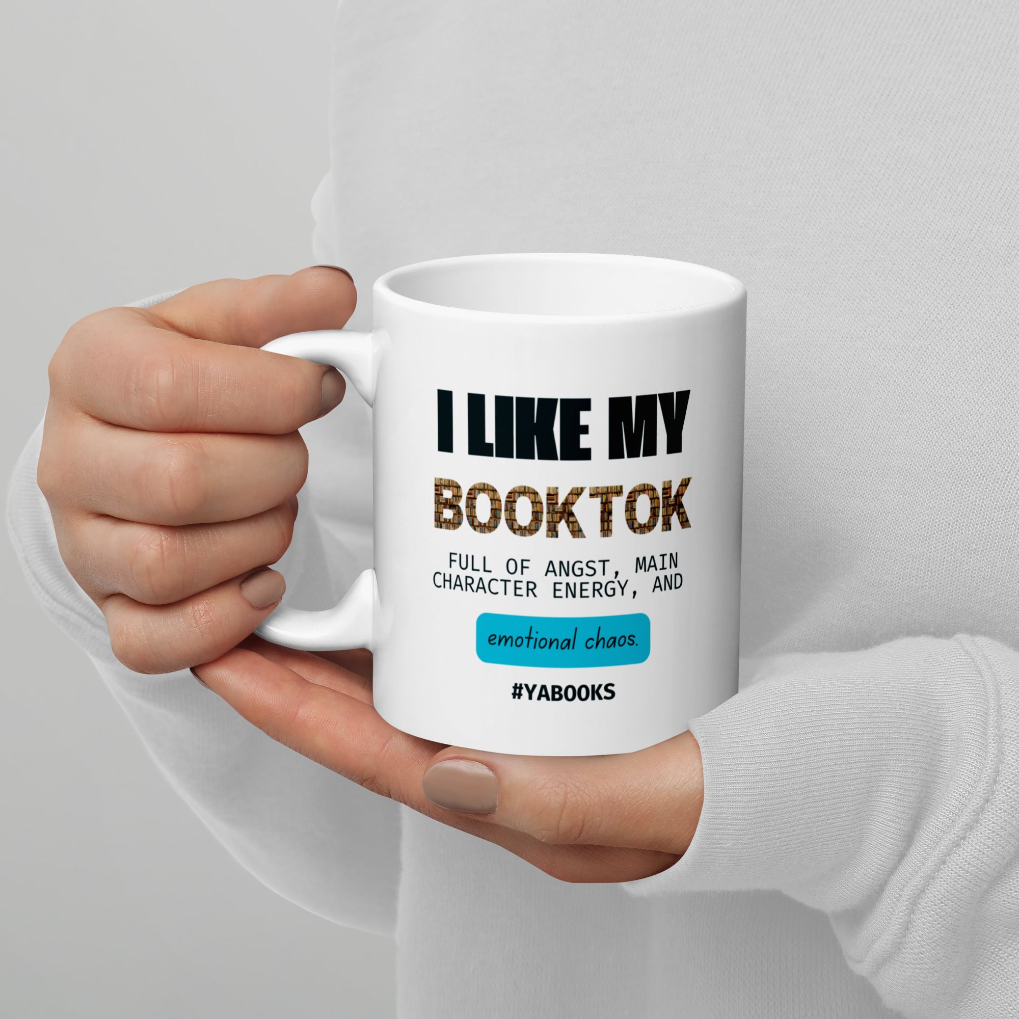Hand holding a white mug with text about book reading preferences on a gray background