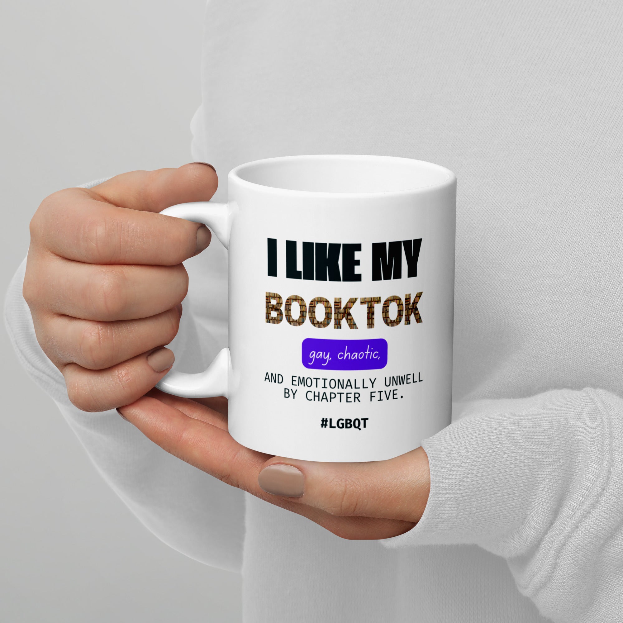 Hand holding a white mug with text design on a gray background