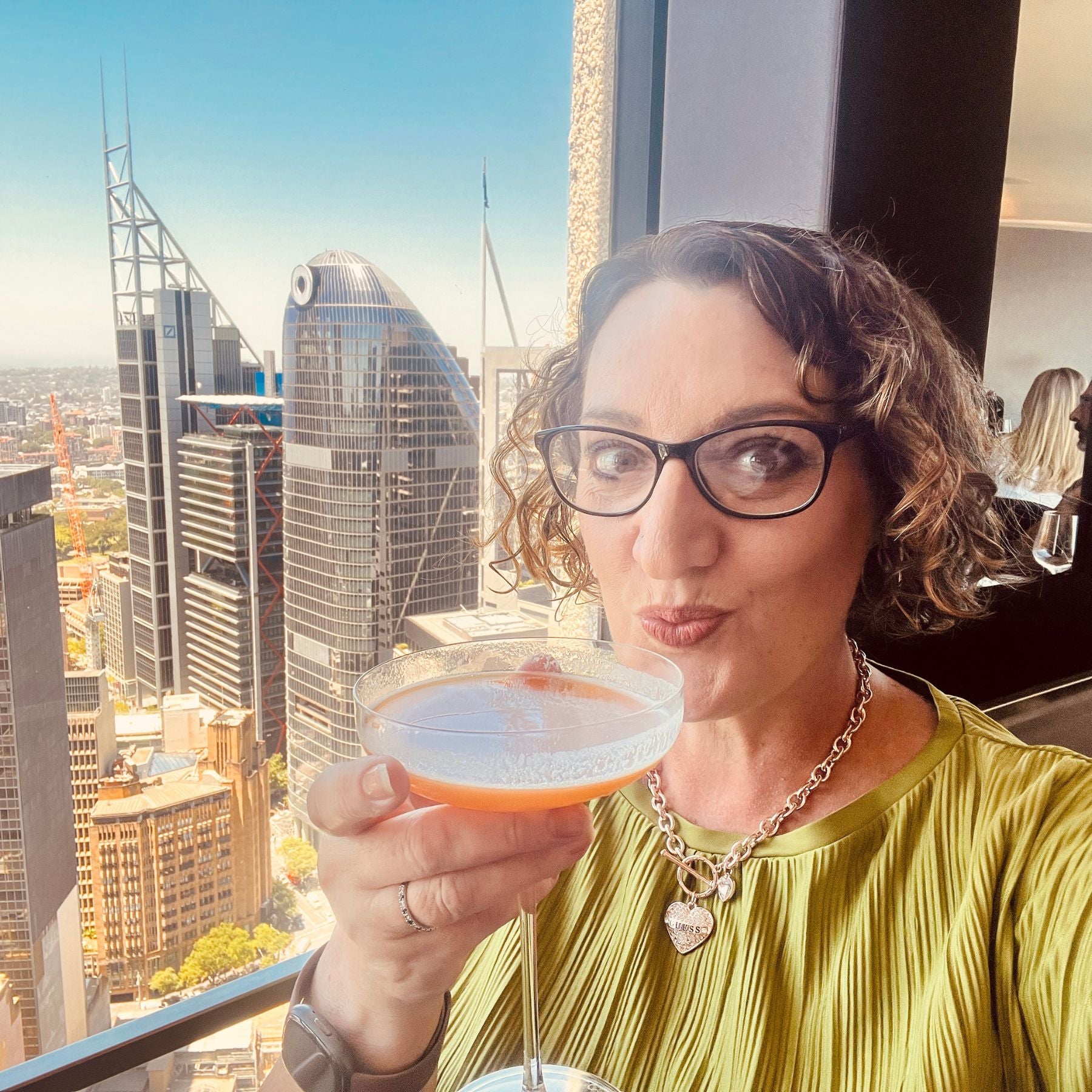 Woman holding a drink with a city skyline in the background