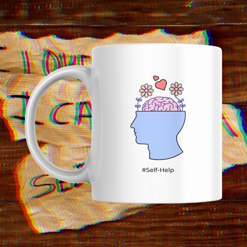 White mug with a graphic of a head with a brain and flowers, and '#Self-Help' text, on a colorful abstract background.