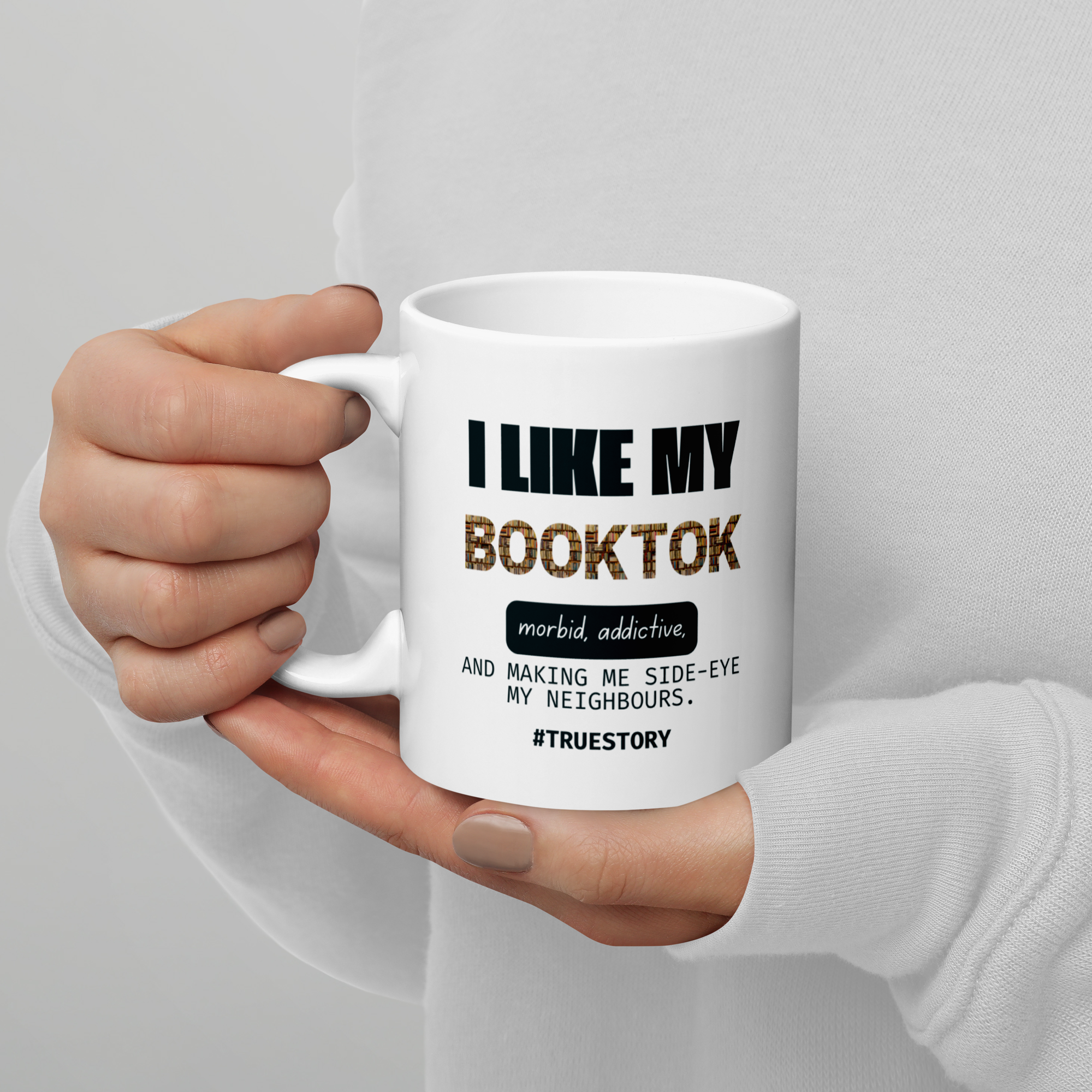 White mug with text held by a hand against a light gray background