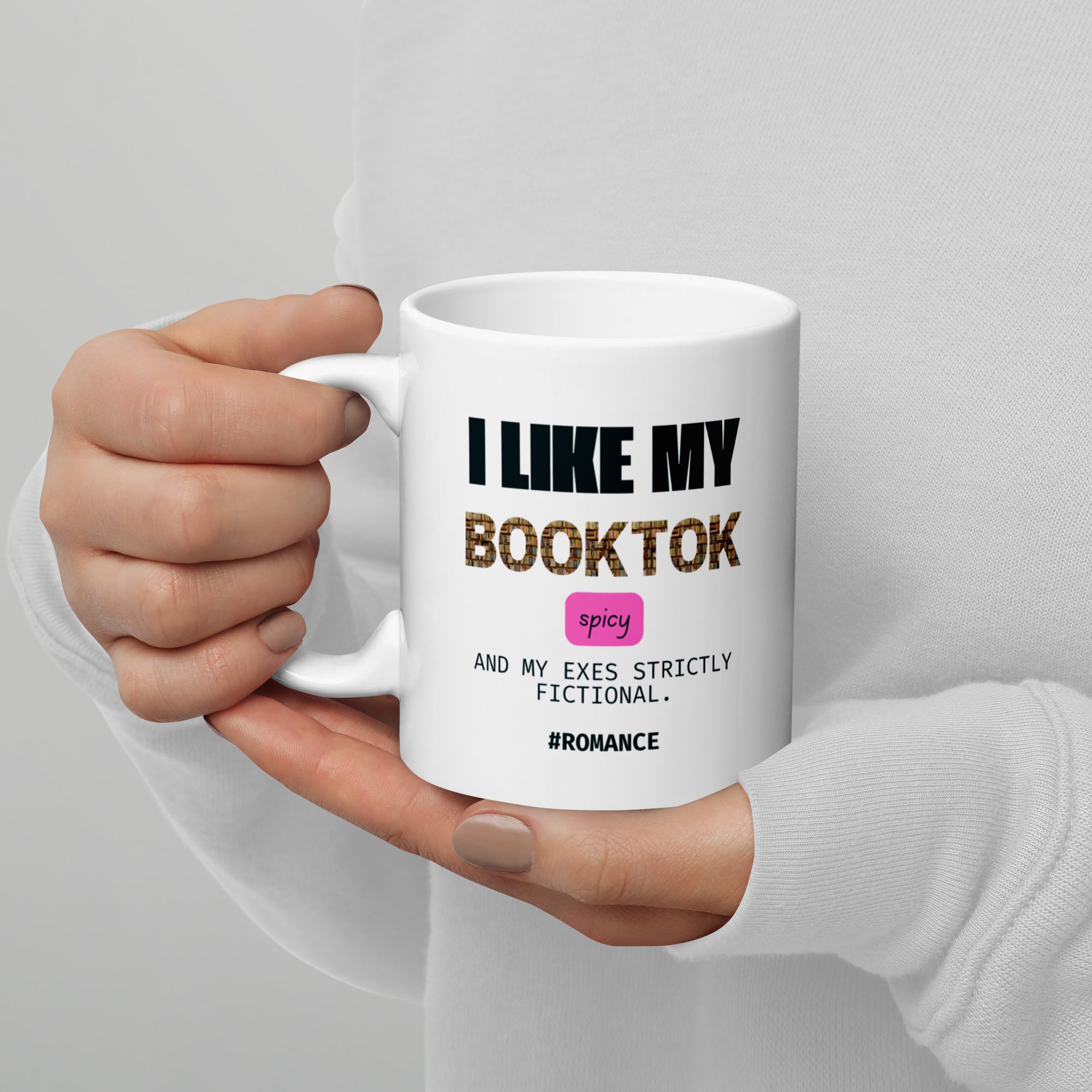 Hand holding a white mug with text design on a gray background