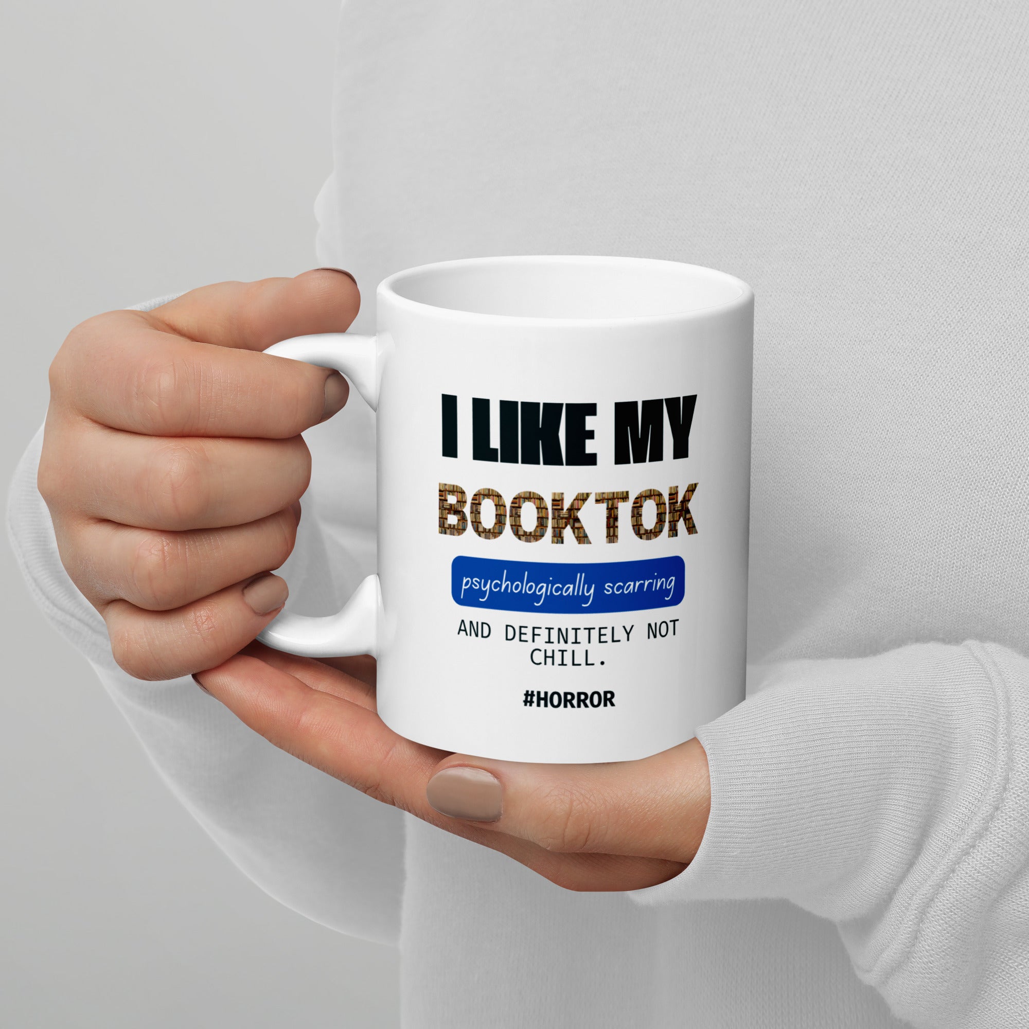 Hand holding a white mug with text design on a gray background