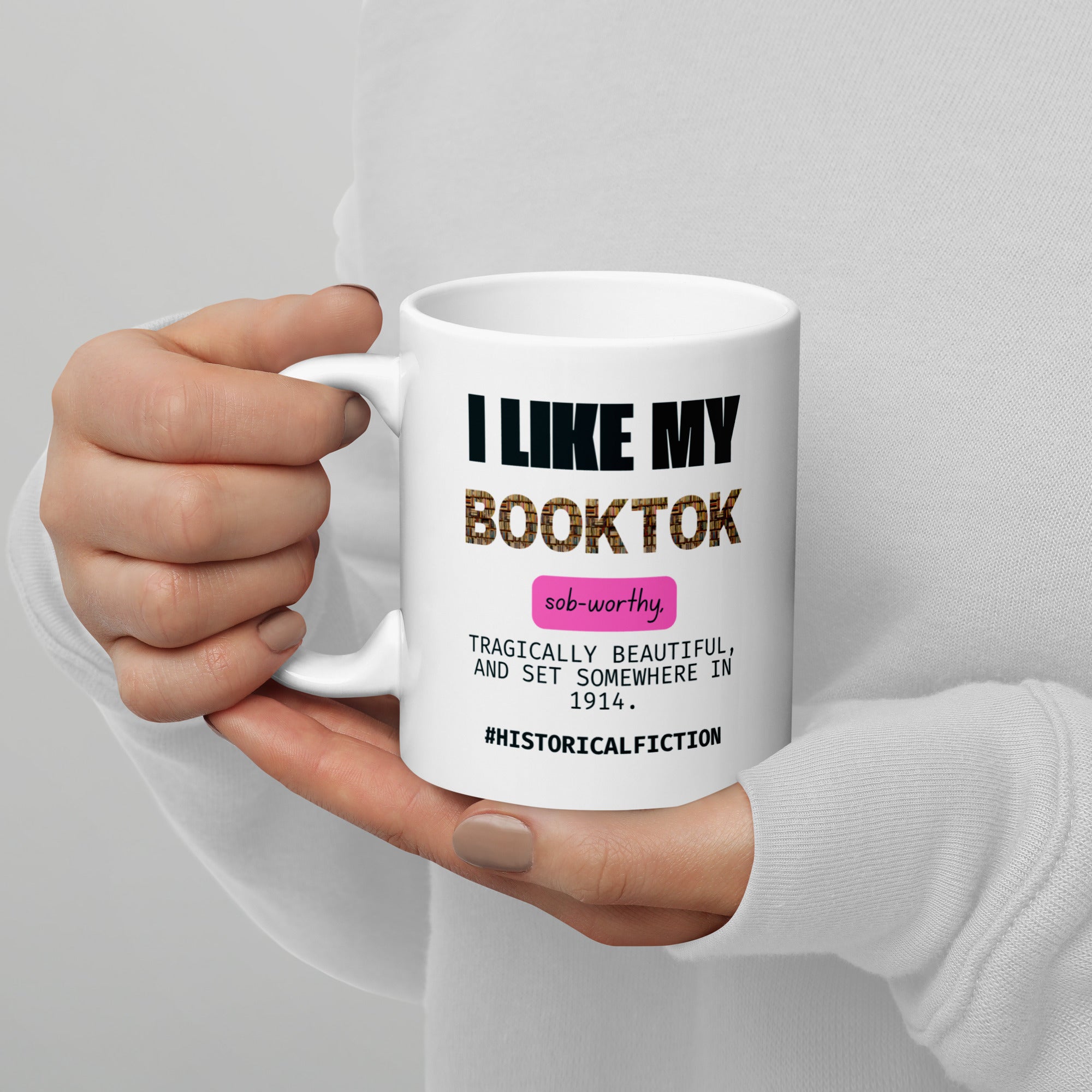 Hand holding a white mug with text design on a gray background