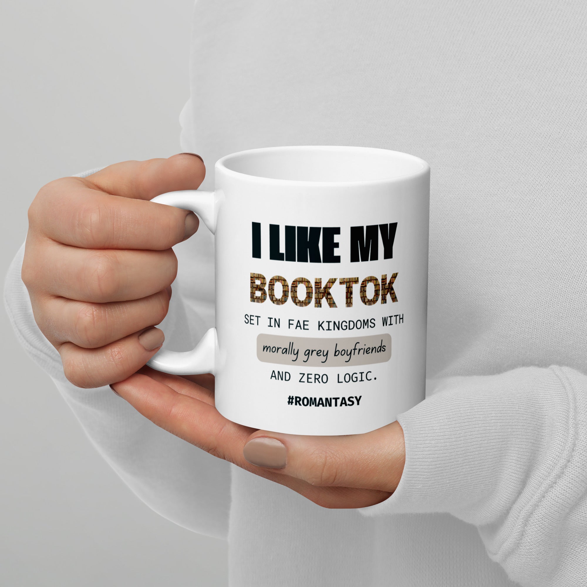White mug with text held by a person against a gray background
