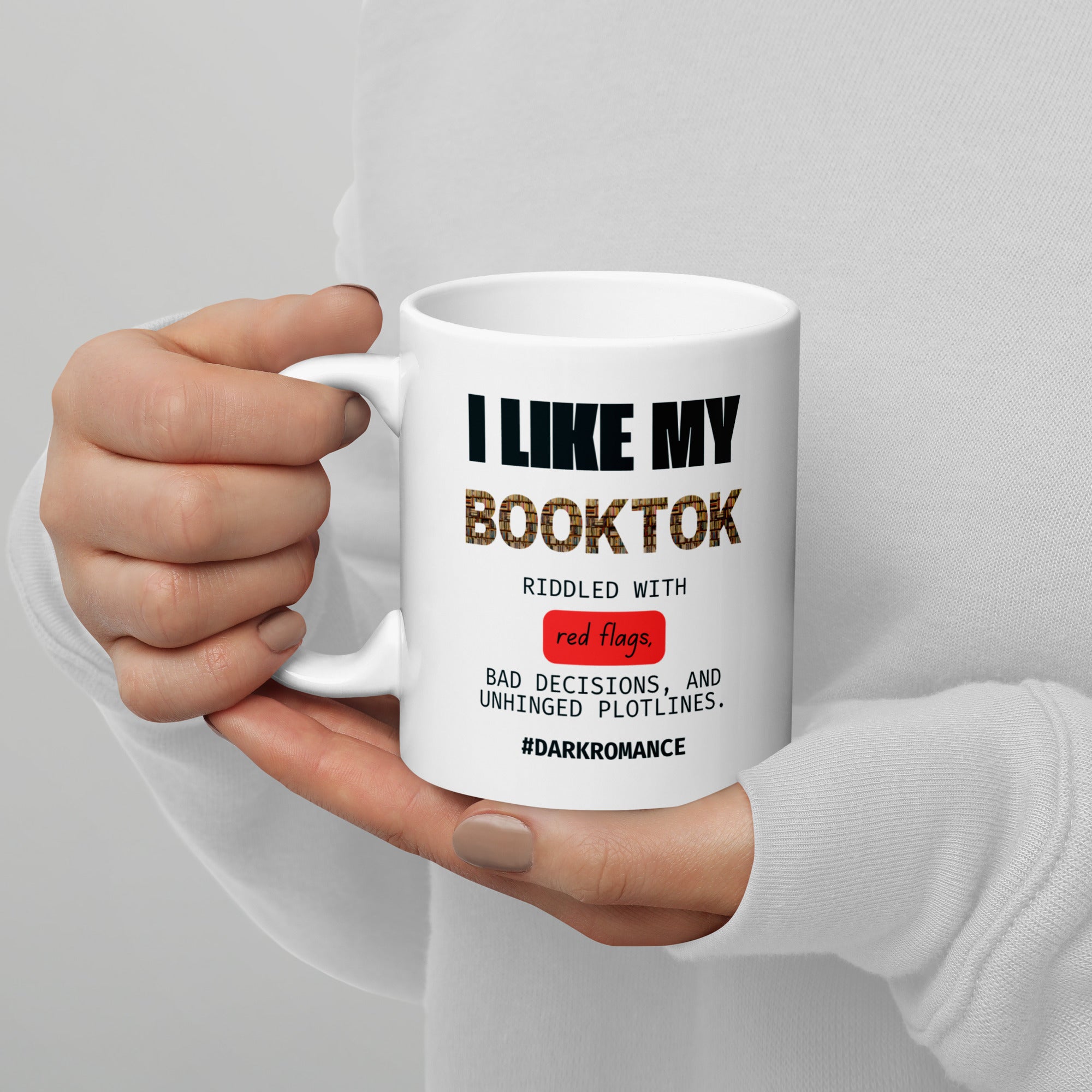 Hand holding a white mug with text design on a gray background