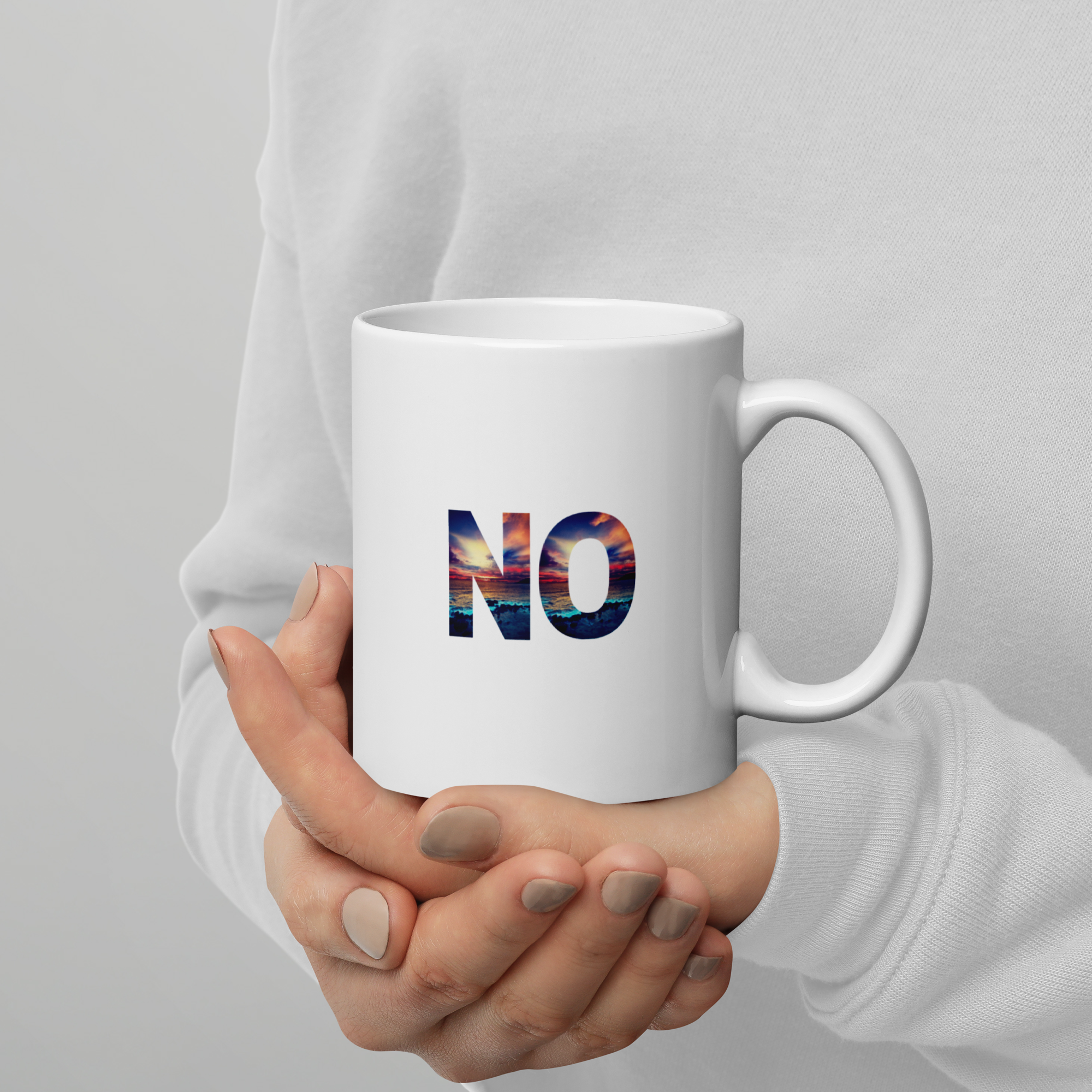 Hand holding a white mug with 'NO' in colorful letters against a gray background