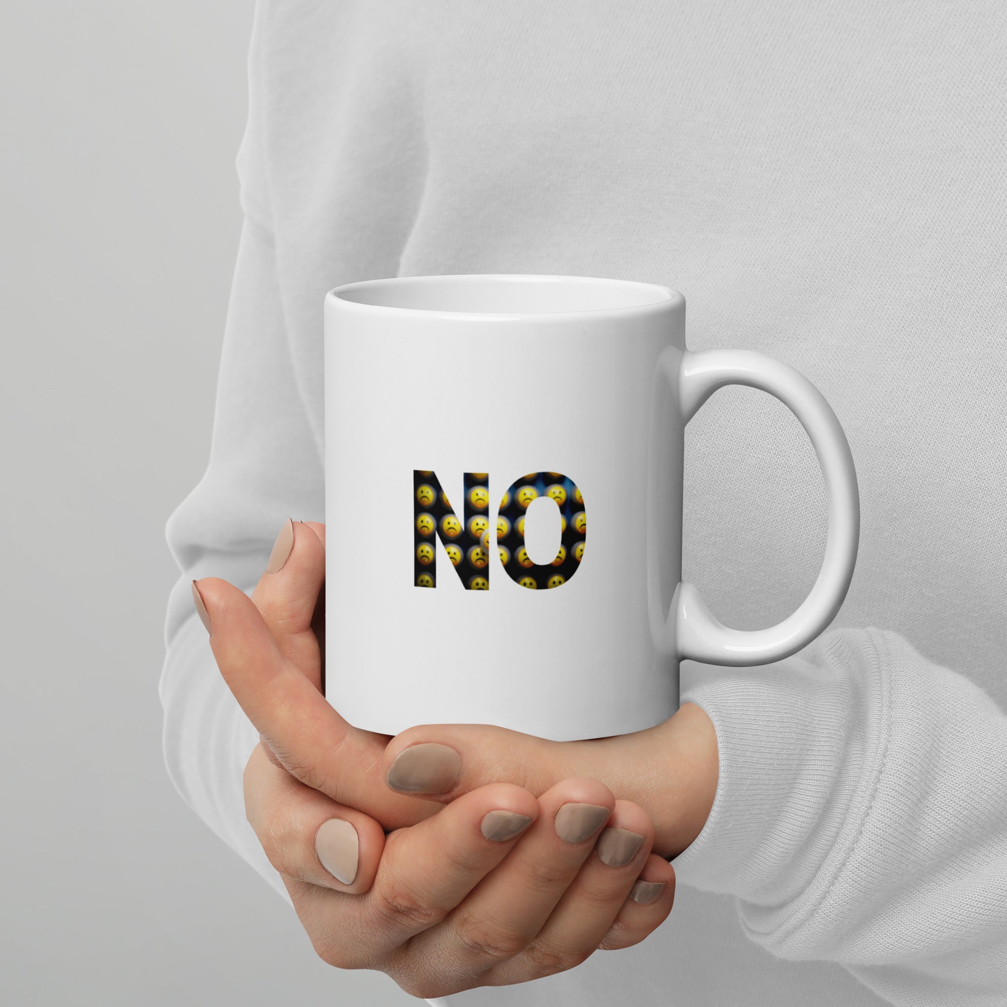 Person holding a white mug with 'NO' text on a plain background